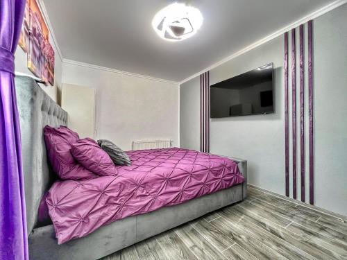 a bedroom with a purple bed and a television at Luxor - Jacuzzi&Cozy Apartments in Sibiu