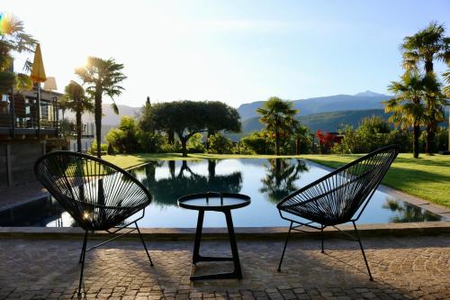 dwa krzesła i stół przed basenem z wodą w obiekcie Das Panorama Dependance w mieście Caldaro