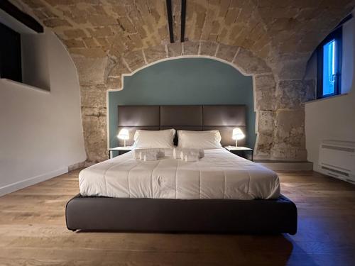 a bedroom with a large bed in a stone wall at PALAZZO SANTAMARINA Luxury Suite & Spa in Palermo