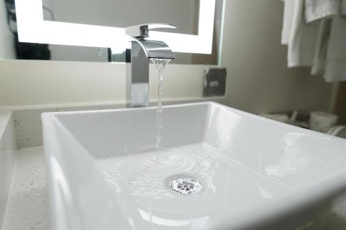 lavabo con agua procedente de un grifo en Marjac Suites Virginia Beach Oceanfront, en Virginia Beach