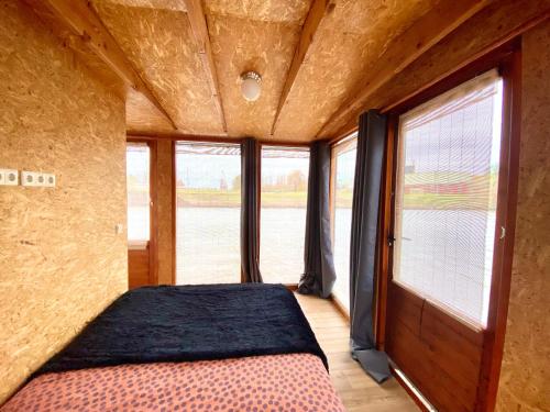 a bedroom with a bed in a room with windows at Off-Grid Boat Experience - Stay Zero Footprint in Utrecht