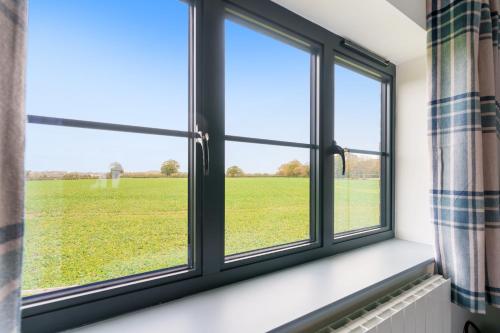 a window with a view of a green field at EASTFIELD HOUSE in Whissonsett
