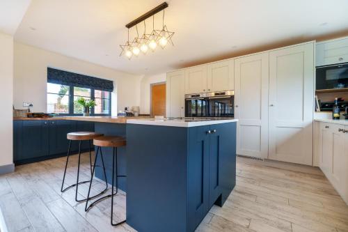 a kitchen with blue island and white cabinets at EASTFIELD HOUSE in Whissonsett