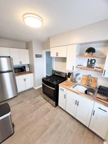 a kitchen with white cabinets and a stove and a sink at The Gateway: Entire Apartment 7 mins from airport in Cleveland