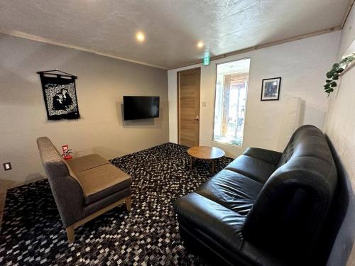 a living room with a black leather couch and a chair at AOBA Hakuba self-contained home in Hakuba