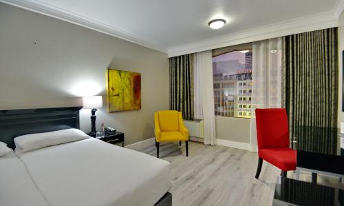 a bedroom with a bed and two chairs and a window at The Capetonian - Halal in Cape Town