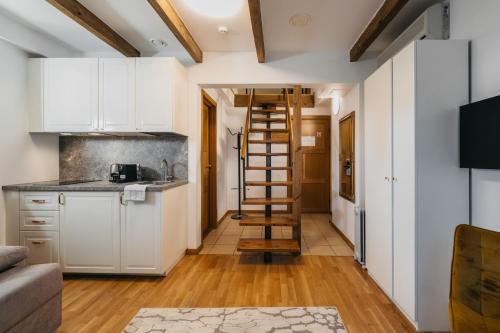 a kitchen with white cabinets and a wooden ladder at CATHEDRAL Old Town Suites in Vilnius