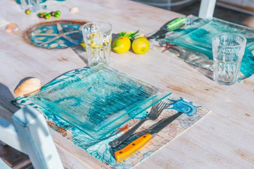 een houten tafel met een blauwe plaat en een glas bij Case Vacanze Il Sogno in Porto Pino