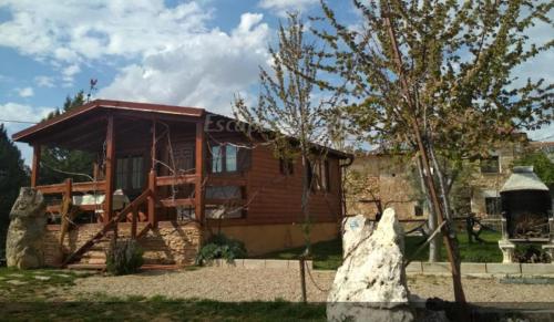 a log house with a tree in front of it at Apartamento EL Paso in Fuentelisendo