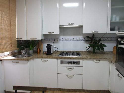cocina con armarios blancos, fogones y fregadero en Elduayen Luxury Centro, en Vigo