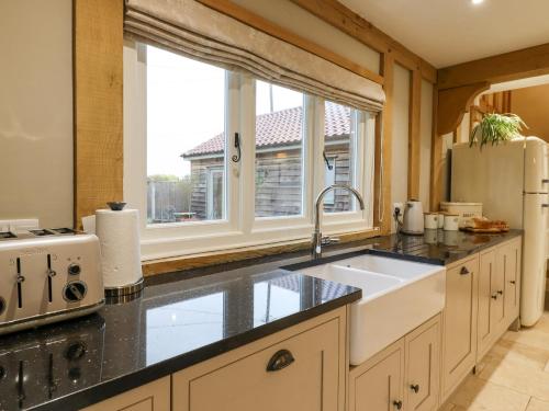 a kitchen with a sink and a large window at Lodge Cottage in Harwich
