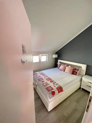 a bedroom with a white bed with red pillows at Banićević APARTMANI in Ðenovići
