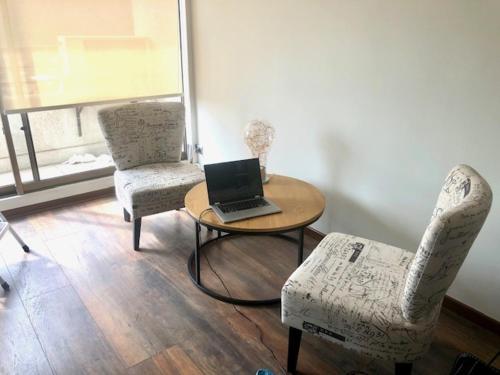 a room with a table and two chairs and a laptop at Lindo y acogedor departamento en Bellavista in Santiago