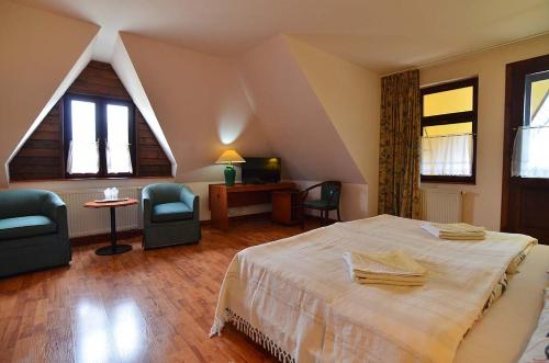 a bedroom with a bed and chairs in a attic at Hotel-EuroPenzión Salaš in Vinné