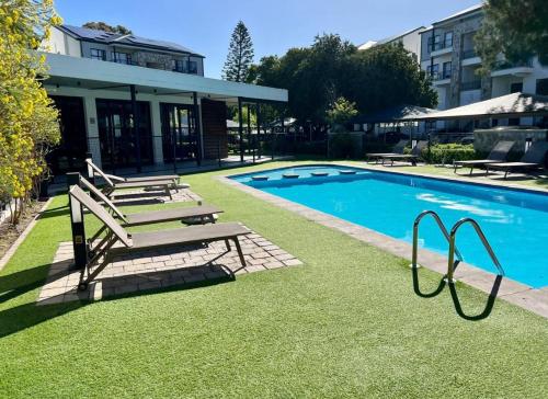 a swimming pool with benches next to a building at Sunny Shores Hideaway in Cape Town
