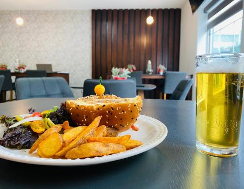 a plate with a sandwich and french fries and a glass of beer at La Quinta by Wyndham Reynosa in Reynosa