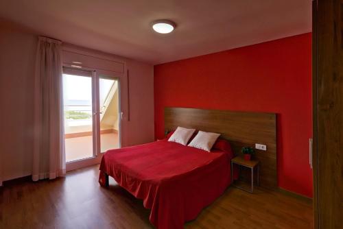 Dormitorio rojo con cama y ventana en Apartamentos Bon Repós, en Santa Susanna