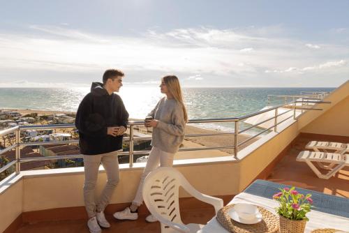 サンタ・スサナにあるApartamentos Bon Repósの海を見渡すバルコニーに立つ男女