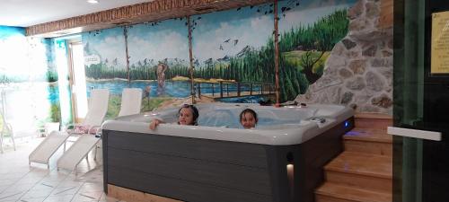 Dos mujeres en una bañera en una habitación en Appartamenti hotel ortles en Cogolo