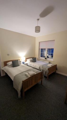 a bedroom with two beds and a window at Cosy Fermanagh Home - The Cosy Beech in Lisnaskea