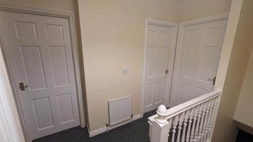 a hallway with two white doors and a staircase at The Cosy Beech in Lisnaskea