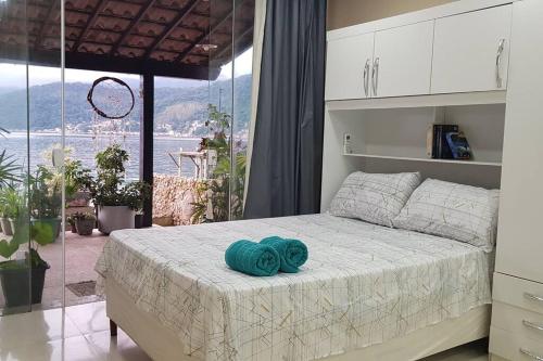 Un dormitorio con una cama con una toalla azul encima. en Casa na Ilha Jardim pé na areia, en Río de Janeiro