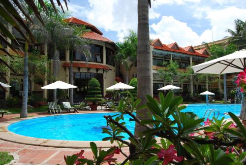 a swimming pool in front of a resort with umbrellas at Tien Dat Resort in Mui Ne