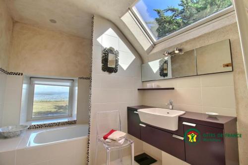 uma casa de banho com um lavatório, uma banheira e uma janela em Fenetres sur le golfe em Sarzeau