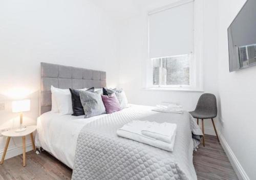 1 dormitorio blanco con 1 cama grande y 1 silla en White Piccadilly en Londres