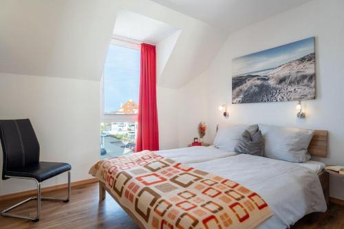 um quarto com uma cama, uma cadeira e uma janela em Strandpark-Grossenbrode-Haus-Windrose-Wohnung-13 em Grossenbrode