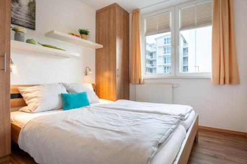 Un dormitorio con una gran cama blanca con ventana. en Strandpark-Grossenbrode-Haus-Meerblick-Wohnung-2, en Großenbrode