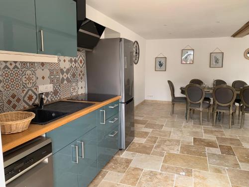 une cuisine avec des placards bleus et une table avec des chaises dans l'établissement Mesnie SAS, à Reugny