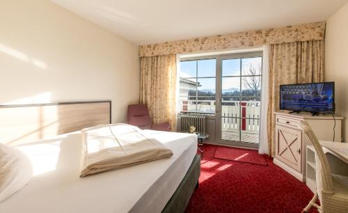sypialnia z łóżkiem i telewizorem oraz balkonem w obiekcie Hotel Sonnenhang w mieście Kempten