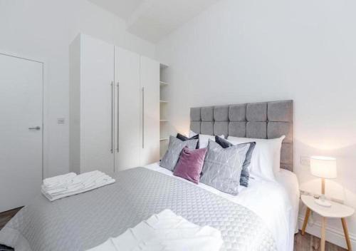 a white bedroom with a large bed with purple pillows at White Piccadilly Luxury Flat in London
