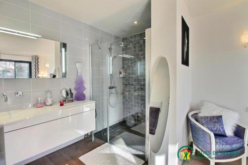 uma casa de banho com uma cabina de duche em vidro e um lavatório. em Mise au vert em Grand-Champ