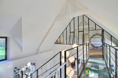 uma escada numa casa com um corrimão de vidro em Mise au vert em Grand-Champ