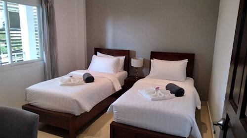 two beds in a hotel room with white sheets at 2 Bedroom Seaview Lanta Sport Resort 303 in Phra Ae beach