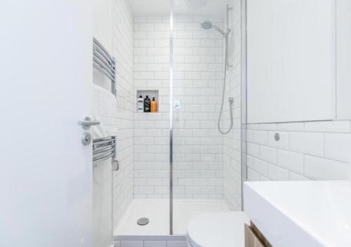 a white bathroom with a shower and a toilet at White Piccadilly Luxury Flat in London