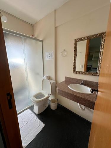 a bathroom with a toilet and a sink and a mirror at Condall Palace Hotel in Nova Prata