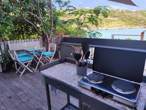 a grill on a deck with a table and chairs at KARETS VIEW les pieds dans l eau - feet in water in Marigot