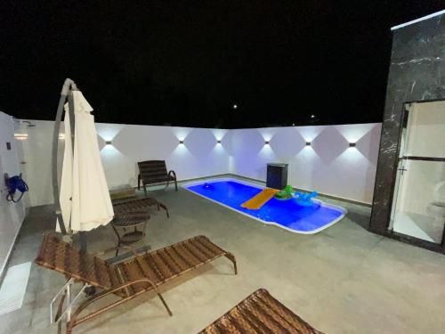 uma piscina com duas cadeiras e um guarda-sol em Casa de praia em Penha em Penha