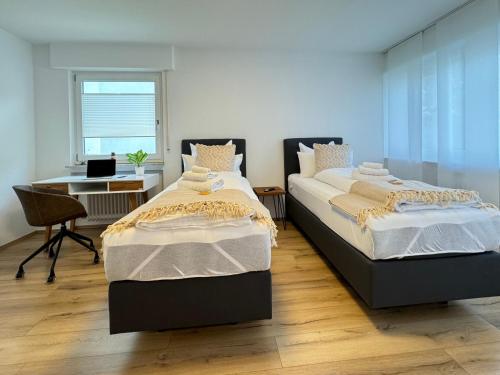 two twin beds in a room with a desk and a desk at 3 Zimmer Apartment, 80 qm, ruhig und zentrumsnah, max 5 Pers, Balkon, Garage, Internet 300 MBit in Sindelfingen