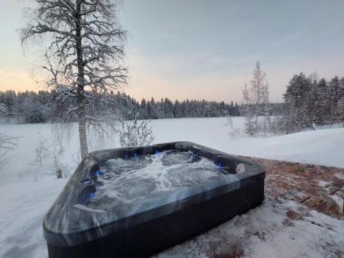 a jacuzzi tub in a snow covered yard at Mökki ulkoporealtaalla in Uurainen