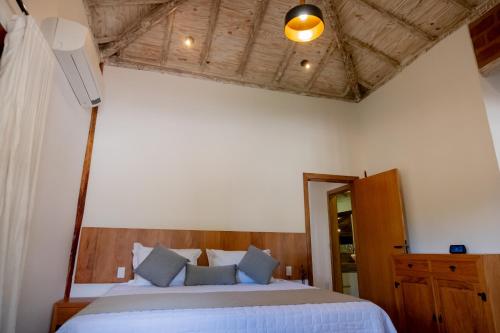 - une chambre avec un lit blanc et une tête de lit en bois dans l'établissement Pousada Rancho Soberbo, Serra do Cipó, à Santana do Riacho
