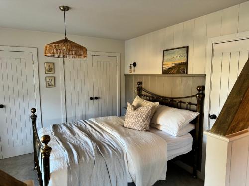 a bedroom with a bed with white sheets and pillows at Appleby Barn in Lacock