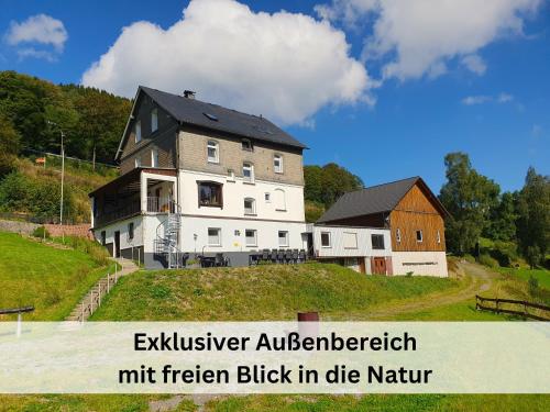 una casa grande en la cima de una colina con un granero en Großes Ferienhaus für 16 Pers mit Indoorspielplatz, Pool, großer Terrasse, Grill, Sauna, Kicker, Dart, uvm - ideal für Familien, en Schmallenberg