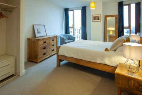 een slaapkamer met een bed, een dressoir en een stoel bij Gorgeous 2BR Apartment with City Views in Leeds