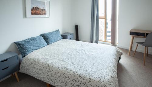 een slaapkamer met een bed, een bureau en een raam bij Gorgeous 2BR Apartment with City Views in Leeds