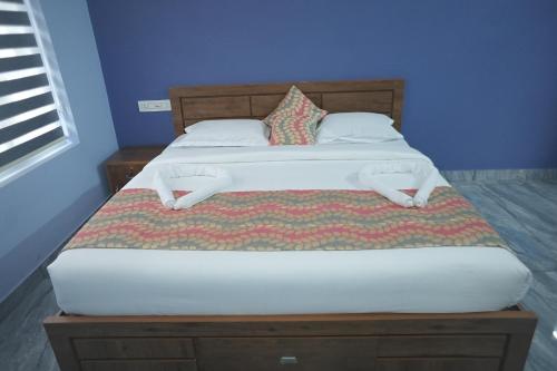 a bedroom with a large bed with a wooden headboard at Luxe Hotel - Rooms & Villas Wayanad in Wayanad