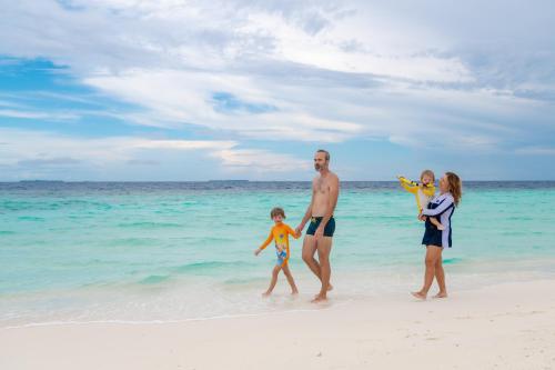 a family walking on the beach on the beach at Biosphere Inn in Dharavandhoo